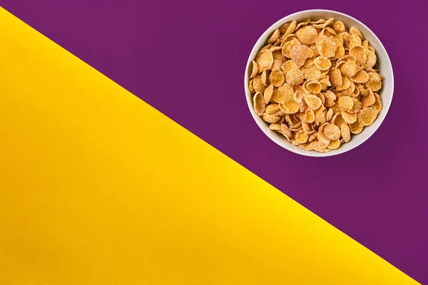 Bowl with cornflakes on the colorful background — Stock Photo, Image