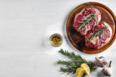 Baharat ve malzemeleri ahşap kesme tahtası ve beyaz arka plan üzerinde yemek pişirmek için ham sığır eti biftek.