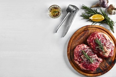 Baharat ve malzemeleri ahşap kesme tahtası ve beyaz arka plan üzerinde yemek pişirmek için ham sığır eti biftek.