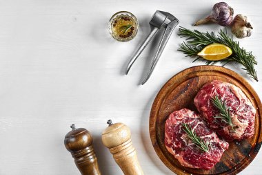 Baharat ve malzemeleri ahşap kesme tahtası ve beyaz arka plan üzerinde yemek pişirmek için ham sığır eti biftek.