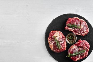 Taze çiğ dana biftek otlar, sarımsak, zeytinyağı, karabiber, tuz ve kara tahta üzerinde biberiye ile: bonfile, Striploin, kaburga