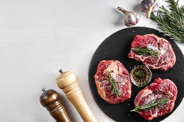Taze çiğ dana biftek otlar, sarımsak, zeytinyağı, karabiber, tuz ve kara tahta üzerinde biberiye ile: bonfile, Striploin, kaburga