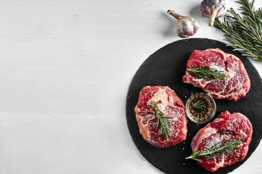 Taze çiğ dana biftek otlar, sarımsak, zeytinyağı, karabiber, tuz ve kara tahta üzerinde biberiye ile: bonfile, Striploin, kaburga