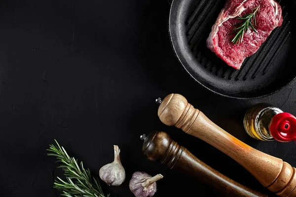 Carne crua fresca. lombo de carne e bifes de carne marmorizada na grelha e frigideira com tempero, fundo preto vista superior . — Fotografia de Stock