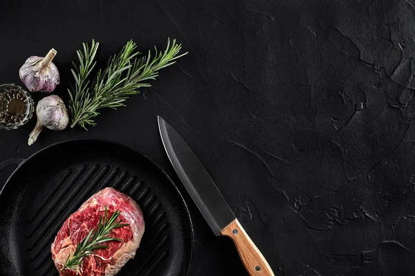 Fresh raw meat. Beef Tenderloin and marbled beef steaks on grill pan and frying board with seasoning, black background top view.