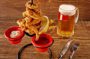 Meyilli ahşap masa üzerinde limon, kırmızı ve beyaz soslar ile kalamar halkaları