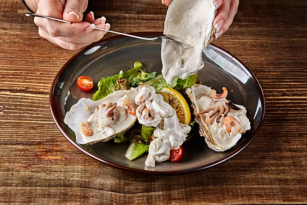 Frutos do mar. Cozinha de restaurante, comida delicatessen saudável. Ostras, camarões, polvo em molho de creme branco na casca de ostras . — Fotografia de Stock