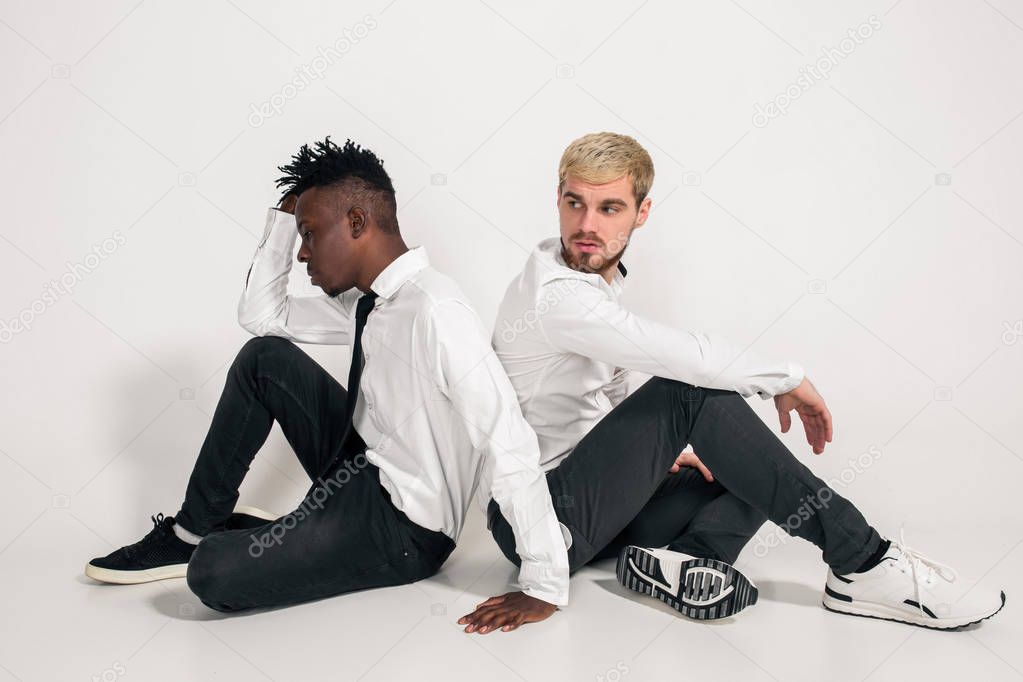 Friends. Two guys in white shirts and dark pants posing in the studio on a white background