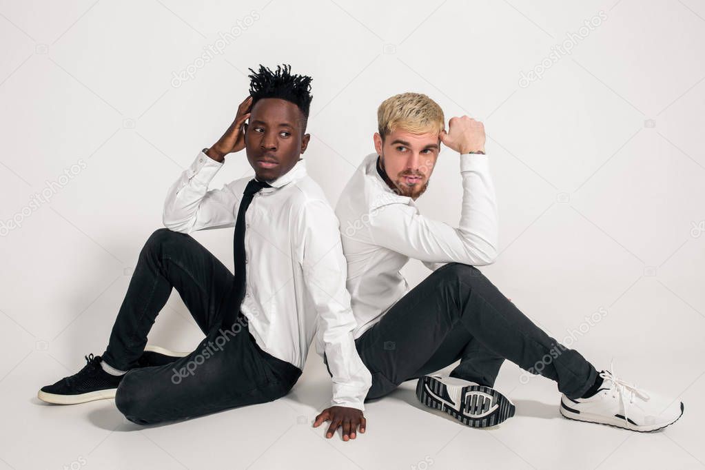 Friends. Two guys in white shirts and dark pants posing in the studio on a white background