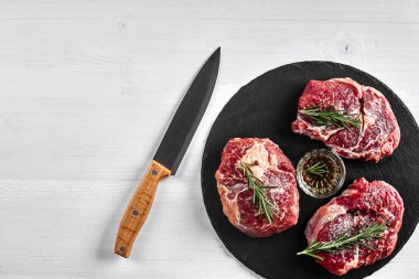 Taze çiğ dana biftek otlar, sarımsak, zeytinyağı, karabiber, tuz ve kara tahta üzerinde biberiye ile: bonfile, Striploin, kaburga