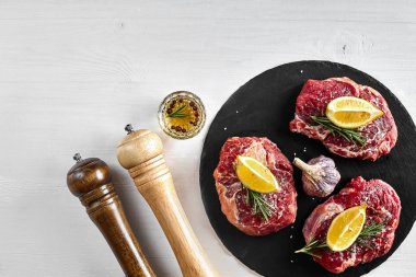 Taze çiğ dana biftek otlar, sarımsak, zeytinyağı, karabiber, tuz ve kara tahta üzerinde biberiye ile: bonfile, Striploin, kaburga