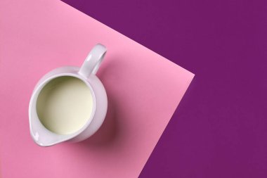 Mor ve pembe arka plan üzerinde taze süt beyaz seramik şişe. Üstten Görünüm