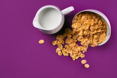 Bir kase mısır gevreği, süt mor arka planda, üstten görünüm sürahi