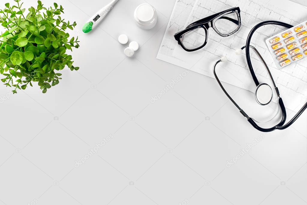 Doctors office desk with medical documents, charts, eyeglasses and stethoscope. Top view. Copy space