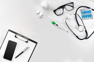 Stetoskop doktor ofisinde. Üstten Görünüm doktorlar Resepsiyon tablo, boş kağıt kalem ile Pano üzerinde. Uzay kopyalayın. Tasarımcılar boş