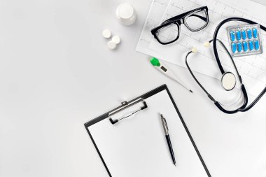 Stetoskop doktor ofisinde. Üstten Görünüm doktorlar Resepsiyon tablo, boş kağıt kalem ile Pano üzerinde. Uzay kopyalayın. Tasarımcılar boş