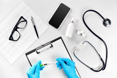 Sıcaklık Ölçüm ve dijital termometre, beyaz arka plan, üstten görünüm üzerinde tıbbi ekipman ile masaüstü tutan doktor