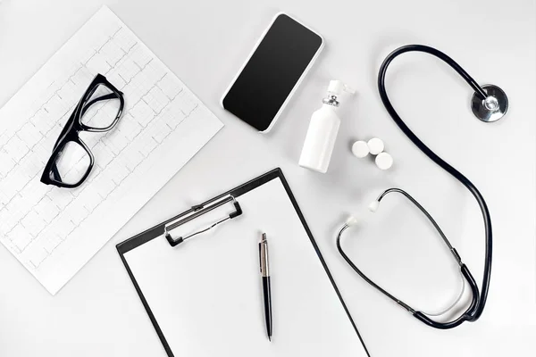 Doctors office desk with medical documents, charts, eyeglasses and stethoscope. Top view. Copy space