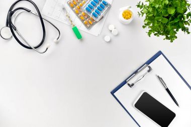 Stetoskop doktor ofisinde. Üstten Görünüm doktorlar Resepsiyon tablo, boş kağıt kalem ile Pano üzerinde. Uzay kopyalayın. Tasarımcılar boş