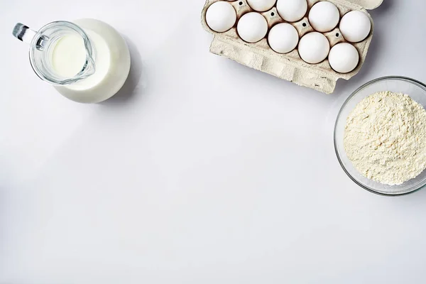 Αλεύρι σίτου σε γυάλινο μπολ, κρέμα γάλακτος σε ένα ποτήρι jar, κοτόπουλο αυγά - υλικά για τη ζύμη, το top view — Φωτογραφία Αρχείου