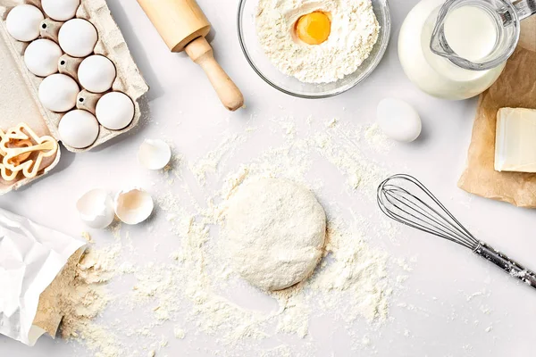 Massa crua pronta para amassar na mesa branca. Ingredientes de padaria, ovos, farinha, manteiga. Formas para fazer biscoitos . — Fotografia de Stock