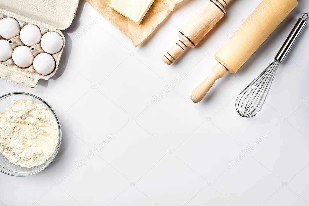 Preparation of the dough. A measurement of the amount of ingredients in the recipe. Ingredients for the dough: flour, eggs, rolling pin, whisk, butter. Top view, space for text