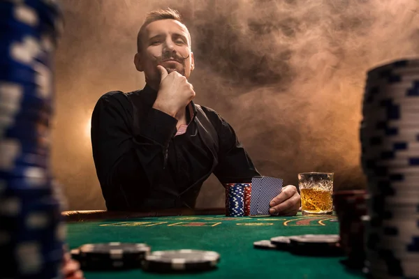Красивий бородатий чоловік п'є віскі, граючи в покер — стокове фото