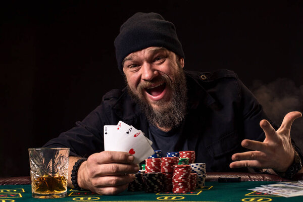 Bearded man drinking whisky while playing poker