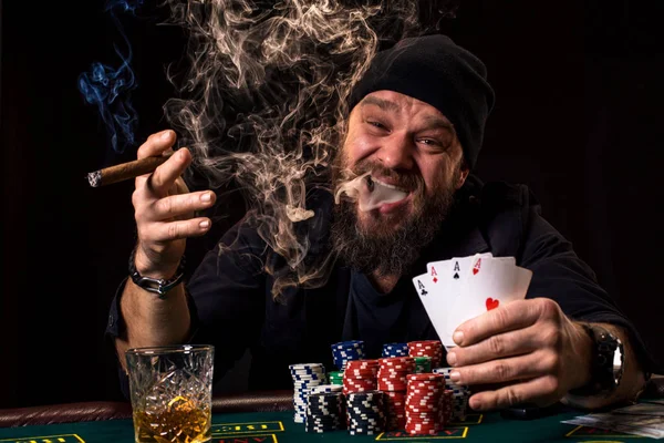 Szakállas ember iszik a whisky és a szivarozva pókerrel — Stock Fotó