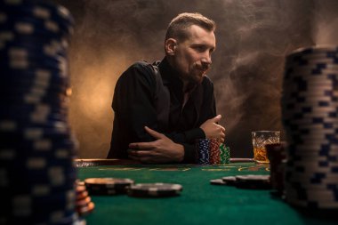 Kartları ve patates kızartması ile poker masasında oturan genç yakışıklı adam