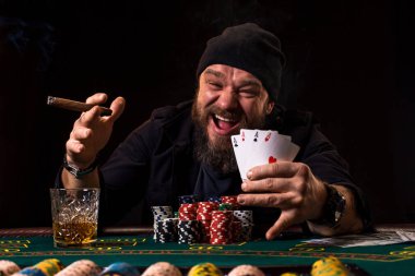 Puro ve bir casino poker masasında oturan cam sakallı adam. Kumar, iskambil ve rulet.