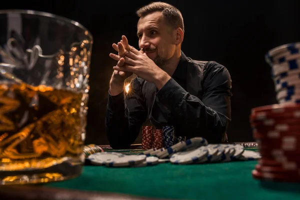 Jonge knappe man achter de pokertafel zit met kaarten en chips — Stockfoto