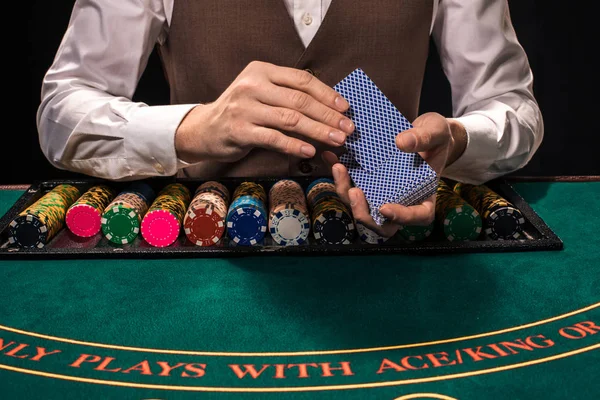 Close up van holdem dealer met speelkaarten en fiches op groene tafel — Stockfoto