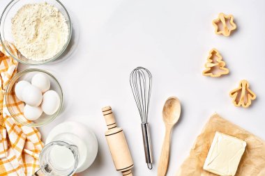Nesneler ve beyaz bir arka plan üzerinde çerez pişirme, plastik kalıpları için malzemeler. Un, yumurta, oklava, çırpma teli, süt, tereyağı, krema. Üstten Görünüm, metin için yer