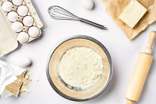 Preparação da massa. Uma medida da quantidade de ingredientes na receita. Ingredientes para a massa: farinha, ovos, rolo, batedor, manteiga. Vista superior, espaço para texto — Fotografia de Stock