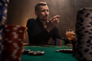 Kartları ve patates kızartması ile poker masasında oturan genç yakışıklı adam
