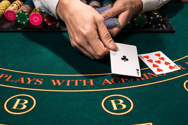 Close up of holdem dealer with playing cards and chips on green table