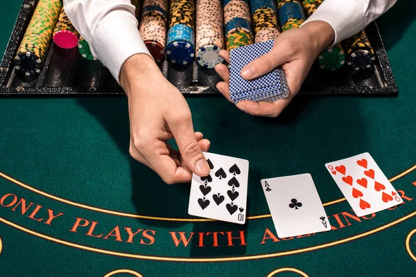 Close up van holdem dealer met speelkaarten en fiches op groene tafel — Stockfoto