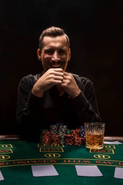 Adam sigara ve viski ile poker oynuyor. Kalın sigara dumanı ile tabloda tüm fişleri kazanan bir adam.