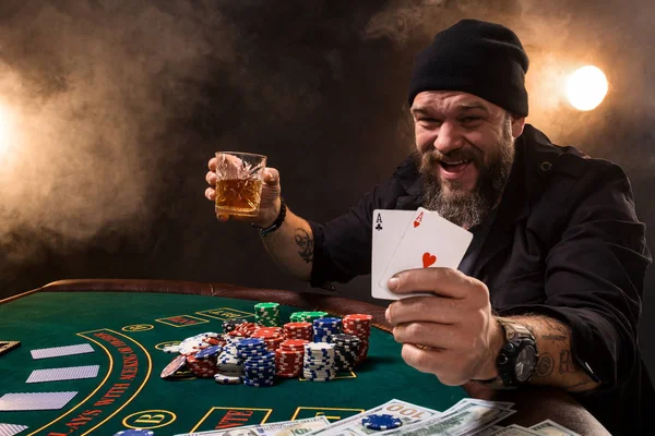 Чоловік грає в покер з сигаретою і віскі, чоловік показує дві карти в руці, вигравши всі фішки на столі з густим сигаретним димом . — стокове фото