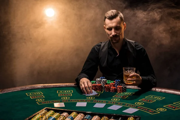 El hombre está jugando al póquer con un cigarro y un whisky. Un hombre ganando todas las fichas en la mesa con humo de cigarrillo grueso . — Foto de Stock