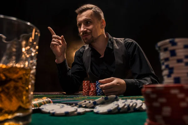 Mann pokert mit Zigarre und Whiskey. ein Mann gewinnt alle Chips auf dem Tisch mit dickem Zigarettenrauch. — Stockfoto
