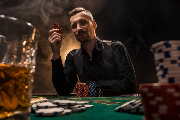 El hombre está jugando al póquer con un cigarro y un whisky. Un hombre ganando todas las fichas en la mesa con humo de cigarrillo grueso . — Foto de Stock