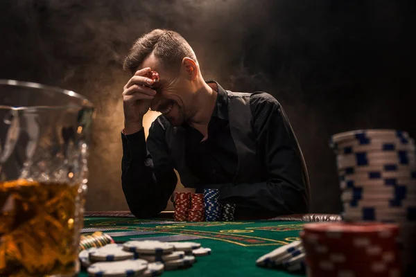 El hombre está jugando al póquer con un cigarro y un whisky. Un hombre ganando todas las fichas en la mesa con humo de cigarrillo grueso . — Foto de Stock