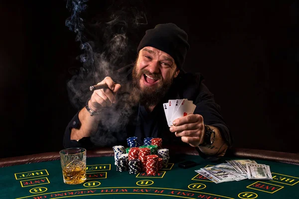 Man spelar poker med en cigarr och en whiskey, en enmansshow två kort i handen, vinna alla marker på bordet med tjock cigarettrök. — Stockfoto