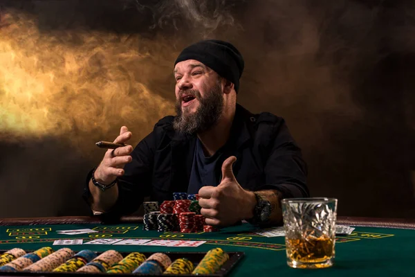 Чоловік грає в покер з сигарою і віскі. Чоловік виграє всі фішки на столі з товстим сигаретним димом . — стокове фото