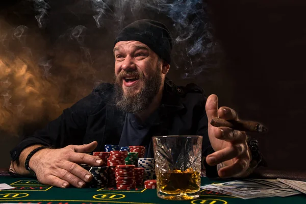 Ο άνθρωπος παίζει πόκερ με ένα πούρο και ένα ουίσκι. Ένας άνθρωπος που κερδίζει όλες τις μάρκες στο τραπέζι με παχύ τσιγάρου. — Φωτογραφία Αρχείου