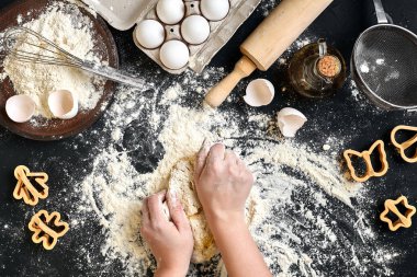 Kadının elleri un, yumurta ve malzemeler ile tabloda hamur yoğurmak. Üstten Görünüm.