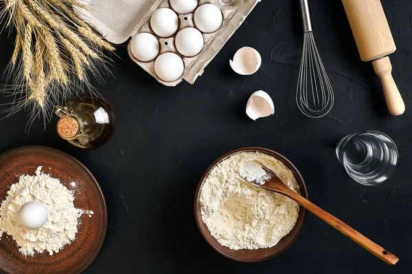 Pasta cooking ingredients on black kitchen table. Top view with space for your text