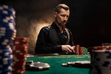 Kartları ve patates kızartması ile poker masasında oturan genç yakışıklı adam